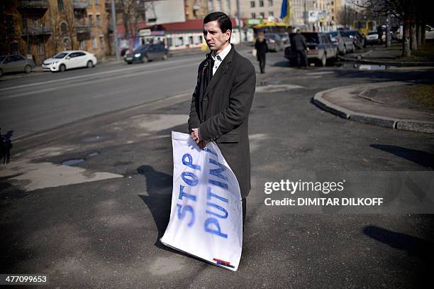 Man holds a banner reading "Stop Putin !" during an anti-war rally in front of the Russian embassy in Kiev on March 7, 2014. Top Russian lawmakers on...