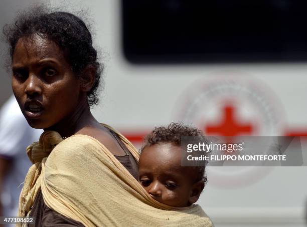 Woman carries her child as she waits next to a vehicle of the Italian Red Cross outside "Baobab" migration centre next to the Tiburtina train station...