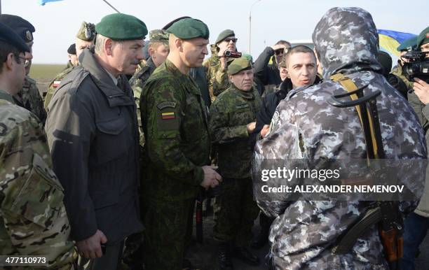 Military observers negotiate with a pro-Russian soldier at the Chongar check point blocking the entrance to Crimea on March 7, 2014. Two buses...