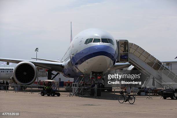 Visitor cycles past a Boeing Inc. 777-300ER aircraft, operated by China Airlines Ltd., at the 51st International Paris Air Show in Paris, France, on...