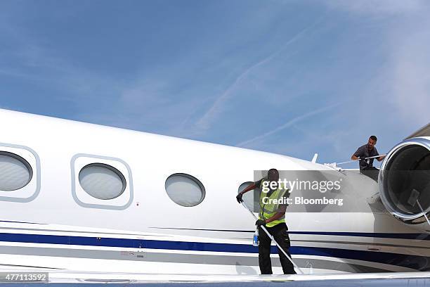 Cleaners polish the fuselage and engine nacelle of a Gulfstream business jet, manufactured by Aerospace Corp., during preparations ahead of the 51st...