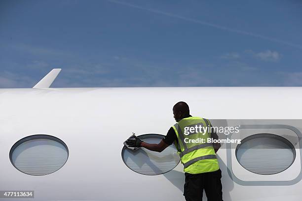 Cleaner polishes the passenger windows of a Gulfstream business jet, manufactured by Aerospace Corp., during preparations ahead of the 51st...