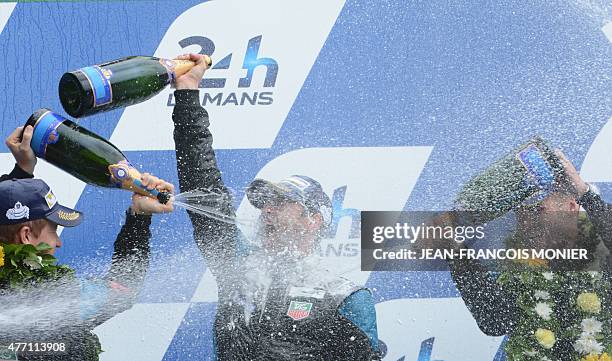 Patrick Dempsey celebrates with champagne next to German's Marco Seefried and US' Patrick Long on the podium of the 83rd Le Mans 24-hours endurance...