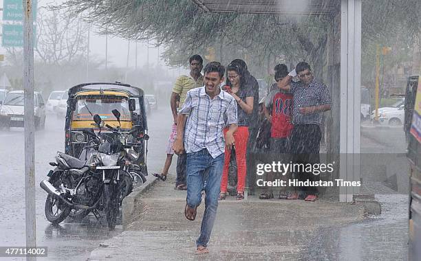 People seek shelter at a bus stop during a heavy rain, on June 14, 2015 in Jaipur, India. The city sizzling as heat wave-like conditions prevailed...