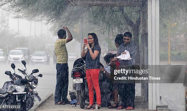 People seek shelter at a bus stop during a heavy rain, on June 14, 2015 in Jaipur, India. The city sizzling as heat wave-like conditions prevailed...