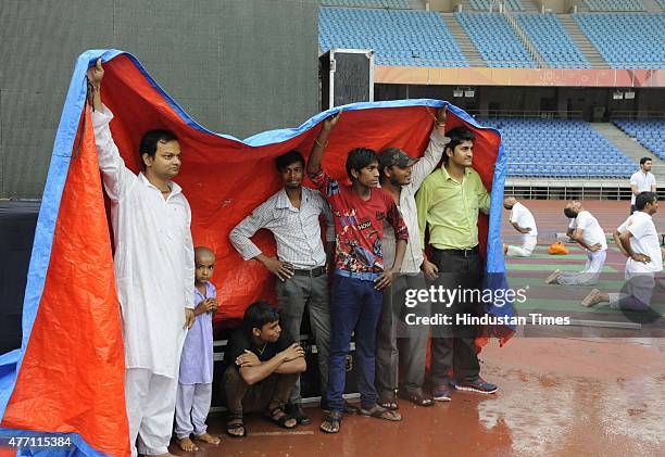 Participants take shelter during the Yoga training camp for the International Yoga Day, organized by Baba Ramdev's Patanjali Yogpeeth under its plan...