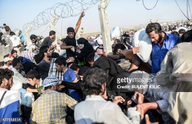Syrians fleeing the war rush through broken down border fences to enter Turkish territory illegally, near the Turkish border crossing at Akcakale in...