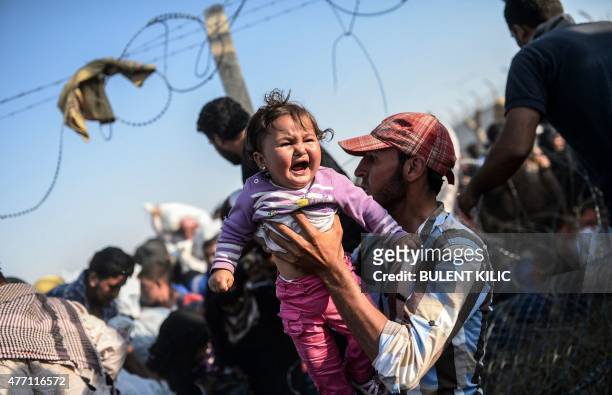 Syrian man fleeing the war carries a child over border fences to enter Turkish territory illegally, near the Turkish border crossing at Akcakale in...