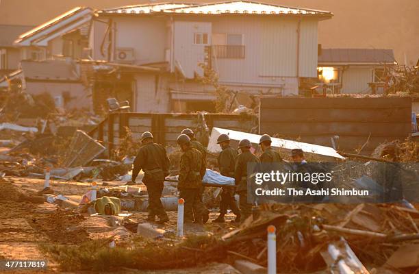 Japan Ground Self-Defense Force members carry a body of the victim after a 9.0 magnitude strong earthquake and subsequent tsunami struck on March 13,...