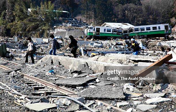 Evacuees walk on the rail track while a derailed carriage remains after a 9.0 magnitude strong earthquake and subsequent tsunami struck on March 13,...