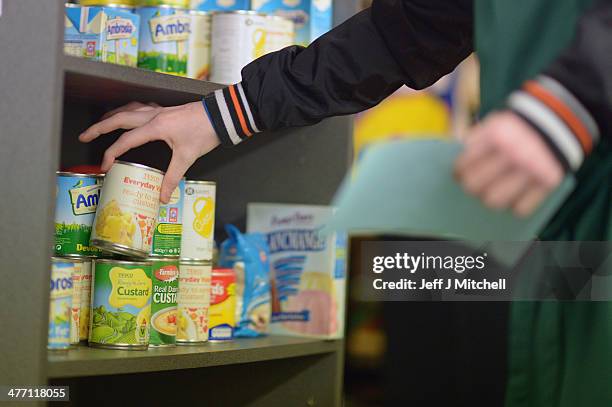 Stuart Little volunteer grabs to pack at a food bank on March 7, 2014 in Whitburn, Scotland. Charities based in Scotland are reporting that many...