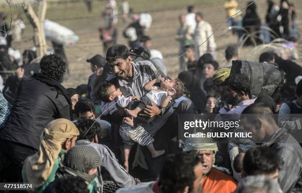 Syrians fleeing the war rush through broken down border fences to enter Turkish territory illegally, near the Turkish border crossing at Akcakale in...