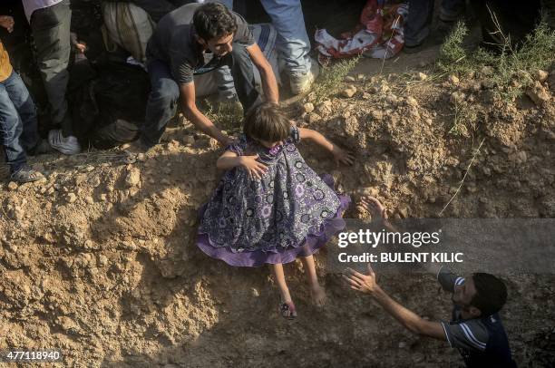 Syrian child fleeing the war is helped as she enters Turkish territory illegally, near the Turkish border crossing at Akcakale in Sanliurfa province...