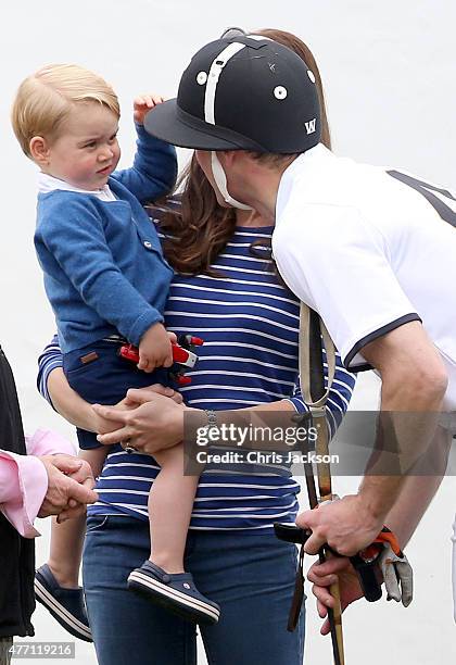 Prince George of Cambridge touches his fathers polo helmet as his mother Catherine, Duchess of Cambridge holds him at the Gigaset Charity Polo Match...