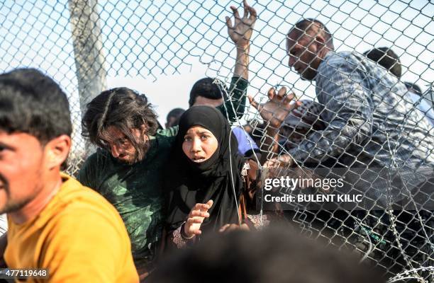 Syrians fleeing the war gather near broken down border fences to enter Turkish territory illegally, near the Turkish border crossing at Akcakale in...