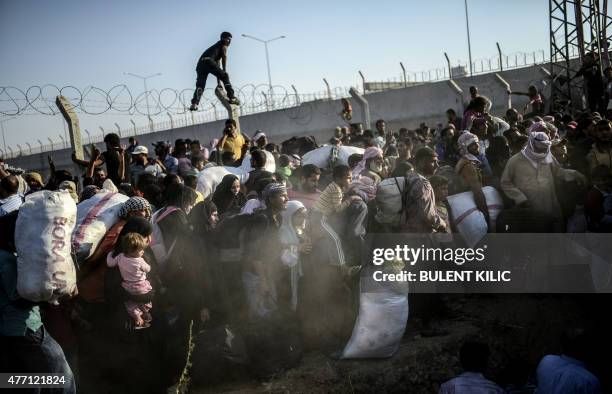 Syrians fleeing the war pass through broken border fences to enter Turkish territory illegally, near the Turkish border crossing at Akcakale in...