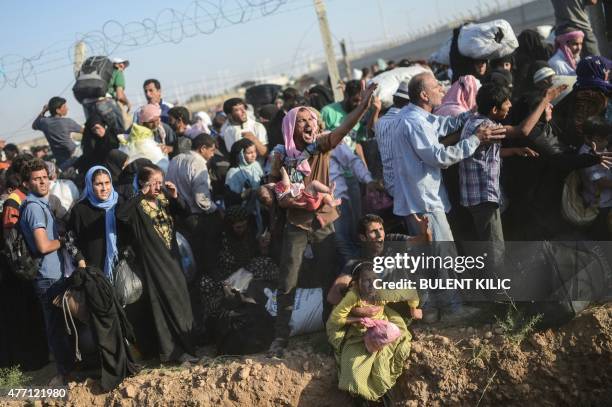 Syrians fleeing the war pass through broken border fences and trenches to enter Turkish territory illegally, near the Turkish border crossing at...