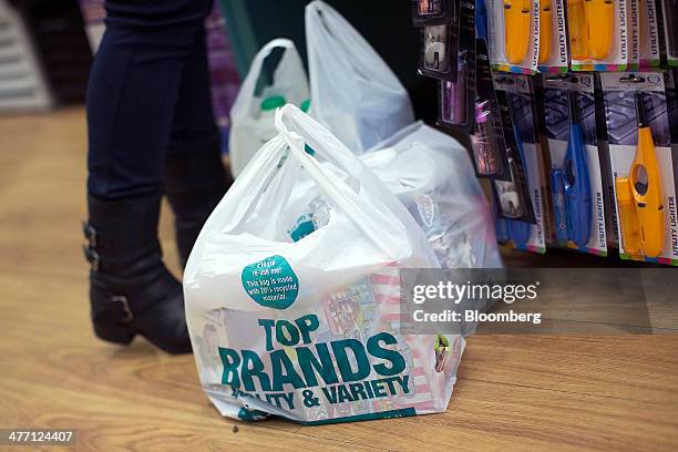 Branded plastic shopping bags containing a customer's goods sit on the shop floor at the check-out desk inside a Poundland discount store, operated...