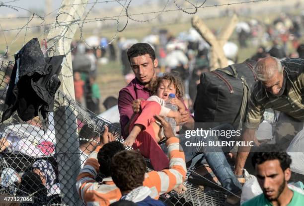 Man carries a girl as Syrians fleeing the war pass through broken down border fences to enter Turkish territory illegally, near the Turkish Akcakale...