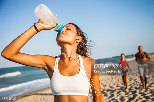 erfrischung nach der körperlichen betätigung bemühungen - woman drinking water from bottle stock-fotos und bilder