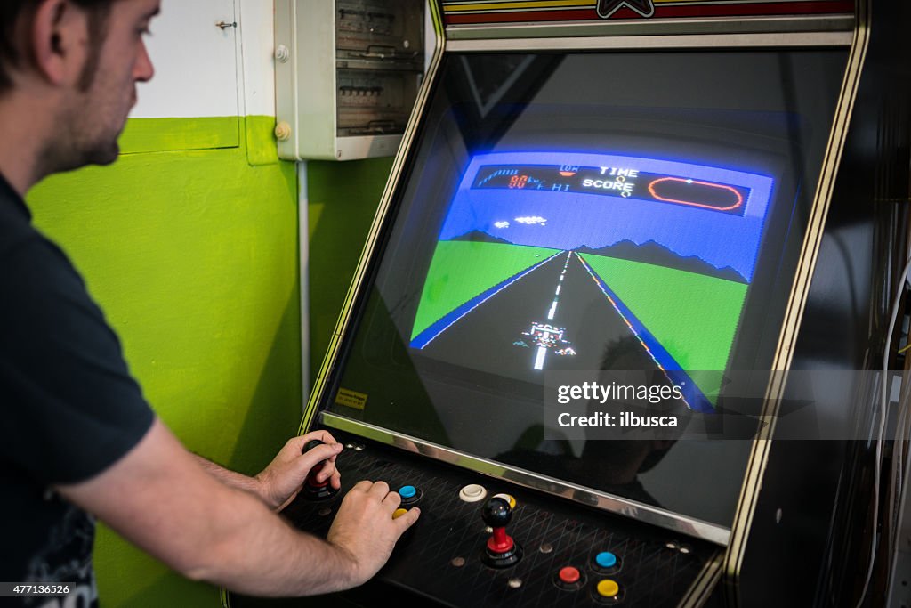 Young man playing vintage arcade videogame