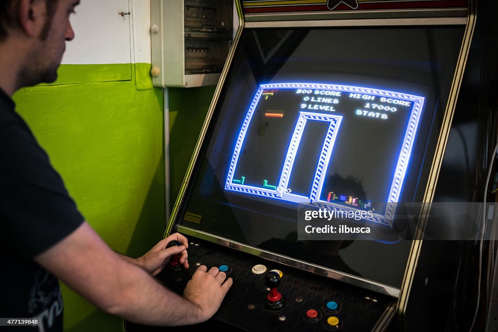 Young man playing vintage arcade videogame