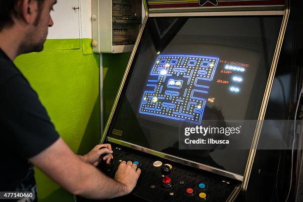 junger mann spielen videospiel-arcade - videospielhalle stock-fotos und bilder