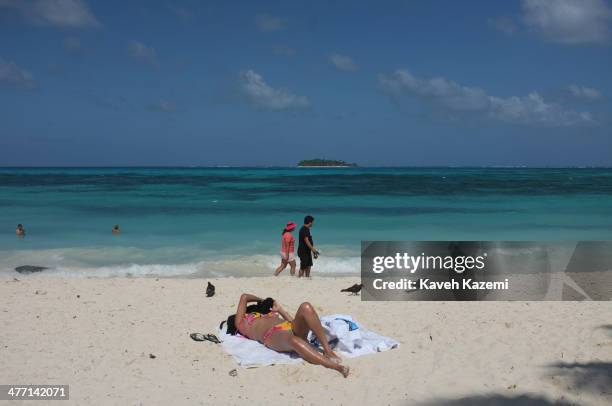 Woman in a bikini with her face covered sunbathes under direct sunlight on the sandy beach on January 26, 2014 in San Andres, Colombia. Colombia has...