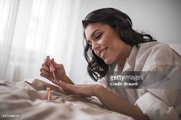 young smiling woman having manicure treatment in bedroom. - nail polish stock pictures, royalty-free photos & images