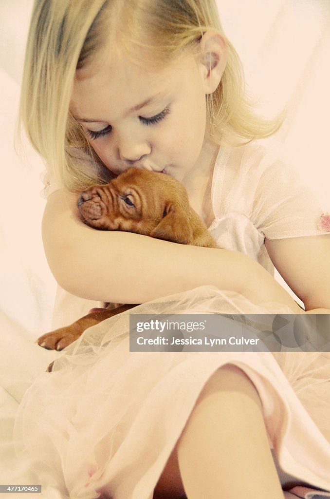 Girl in a pink dress with a puppy