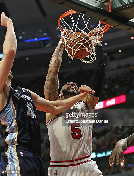 Carlos Boozer of the Chicago Bulls dunks against Kosta Koufos of the Memphis Grizzlies at the United Center on March 7, 2014 in Chicago, Illinois....