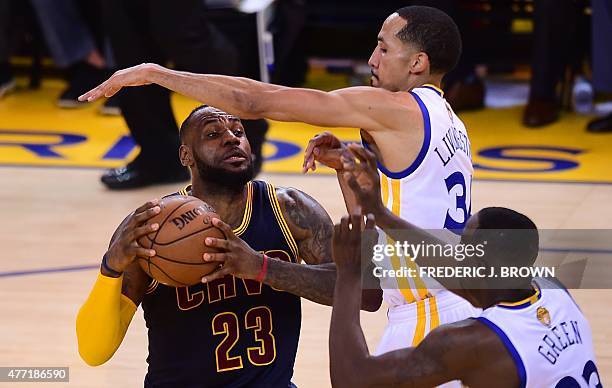 LeBron James of the Cleveland Cavaliers looks to pass under pressure from Shaun Livingston and Draymond Green of the Golden State Warriors during...