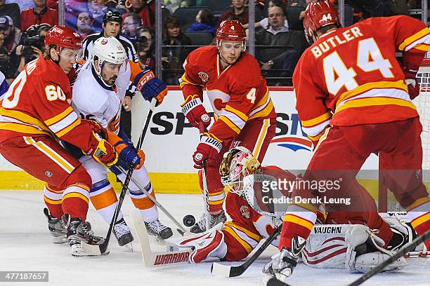 Joni Ortio of the Calgary Flames stops the shot of Cal Clutterbuck of the New York Islanders during an NHL game at Scotiabank Saddledome on March 7,...