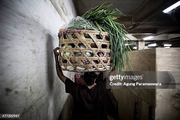 An Indonesian female porter carries a basket of vegetables on her head at Badung traditional market on March 8, 2014 in Denpasar, Bali, Indonesia....