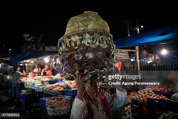 An Indonesian female porter carries a basket of merchandise on her head at Badung traditional market on March 8, 2014 in Denpasar, Bali, Indonesia....