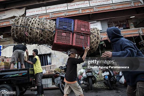 An Indonesian female porter carries baskets on her head at Badung traditional market on March 8, 2014 in Denpasar, Bali, Indonesia. Today, around the...
