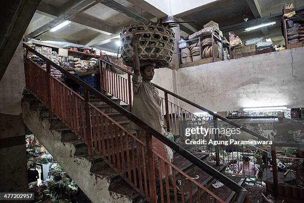 An Indonesian female porter carries a basket of dry goods on her head at Badung traditional market on March 8, 2014 in Denpasar, Bali, Indonesia....