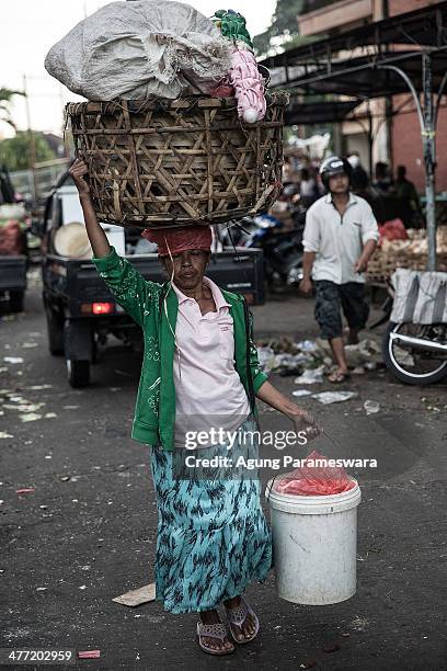 An Indonesian female porter carries baskets and vegetables on her head at Badung traditional market on March 8, 2014 in Denpasar, Bali, Indonesia....