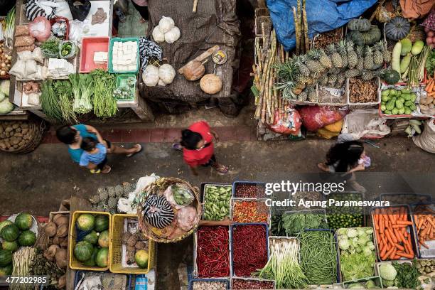 An Indonesian female porter carries a basket of vegetables and meats on her head at Badung traditional market on March 8, 2014 in Denpasar, Bali,...