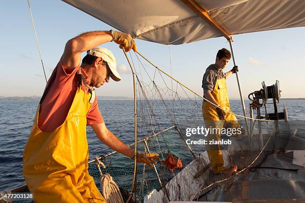 fishermen working on the boat. - industrial fishing net stock pictures, royalty-free photos & images