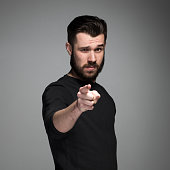 Young man with beard and mustaches, finger pointing towards the