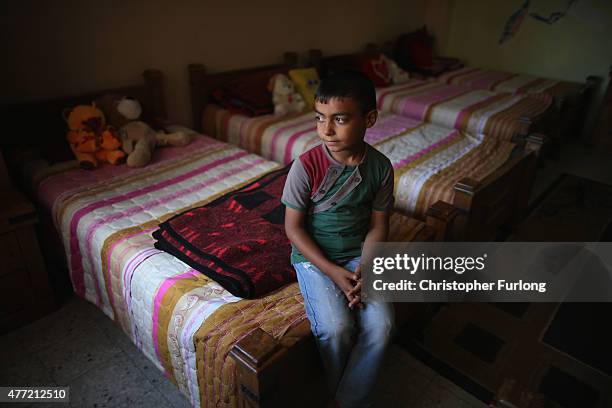 Orphan Mohammed Elghora, aged 8, sits on his bed in the Al-amal Institute for Orphans on June 14, 2015 in Gaza City, Gaza. Mohammed is one of the...