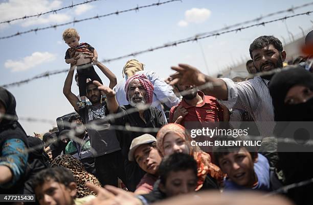 Syrians fleeing the war wait to enter Turkey near the Turkish border crossing at Akcakale in Sanliurfa province on June 15, 2015. Turkey said it was...