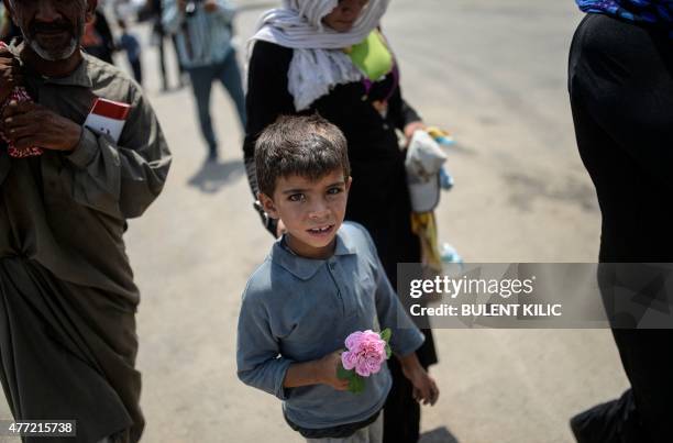 Syrian boy holds a rose after arriving in Turkey at the Akcakale border crossing, in Sanliurfa province on June 15, 2015. Turkey said it was taking...
