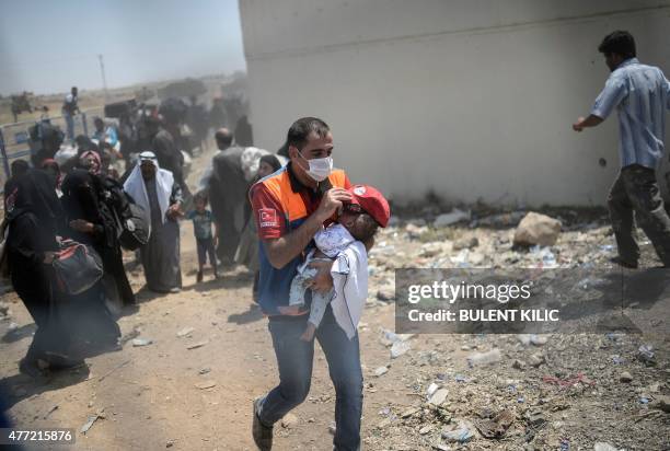 Turkish official carries a child as Syrians fleeing the war walk towards the border gates at the Akcakale border crossing, in Sanliurfa province on...