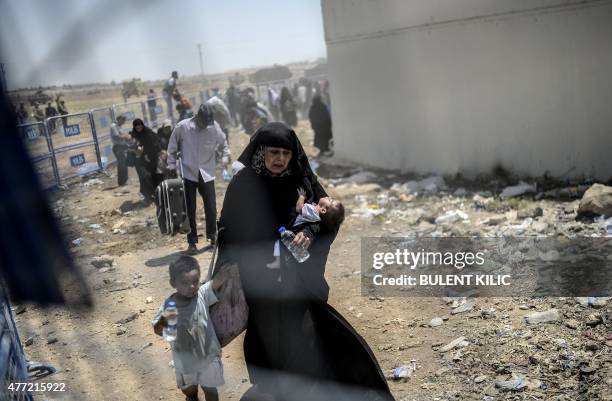 Syrians fleeing the war walk towards the border gates at the Akcakale border crossing, in Sanliurfa province on June 15, 2015. Turkey said it was...