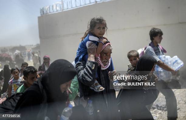 Syrians fleeing the war walk towards the border gates at the Akcakale border crossing, in Sanliurfa province on June 15, 2015. Turkey said it was...