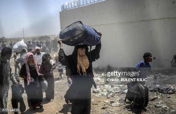 Syrians fleeing the war walk towards the border gates at the Akcakale border crossing, in Sanliurfa province on June 15, 2015. Turkey said it was...