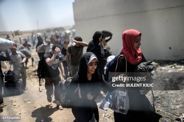 Syrians fleeing the war walk towards the border gates at the Akcakale border crossing, in Sanliurfa province on June 15, 2015. Turkey said it was...