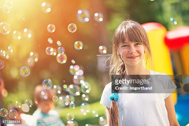 happy little girl and bubbles at the outdoors kids party - bubbles happy stockfoto's en -beelden
